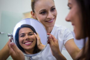 Mulher jovem analisando o rosto no espelho em clínica estética