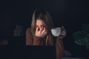 mulher com enxaqueca segurando xícara de café