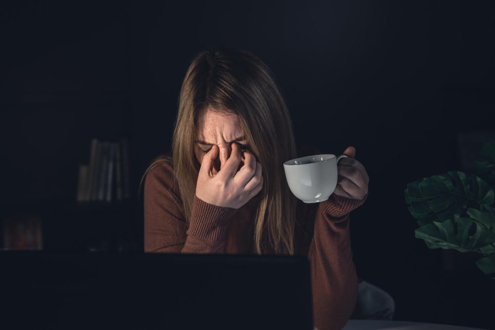 mulher com enxaqueca segurando xícara de café