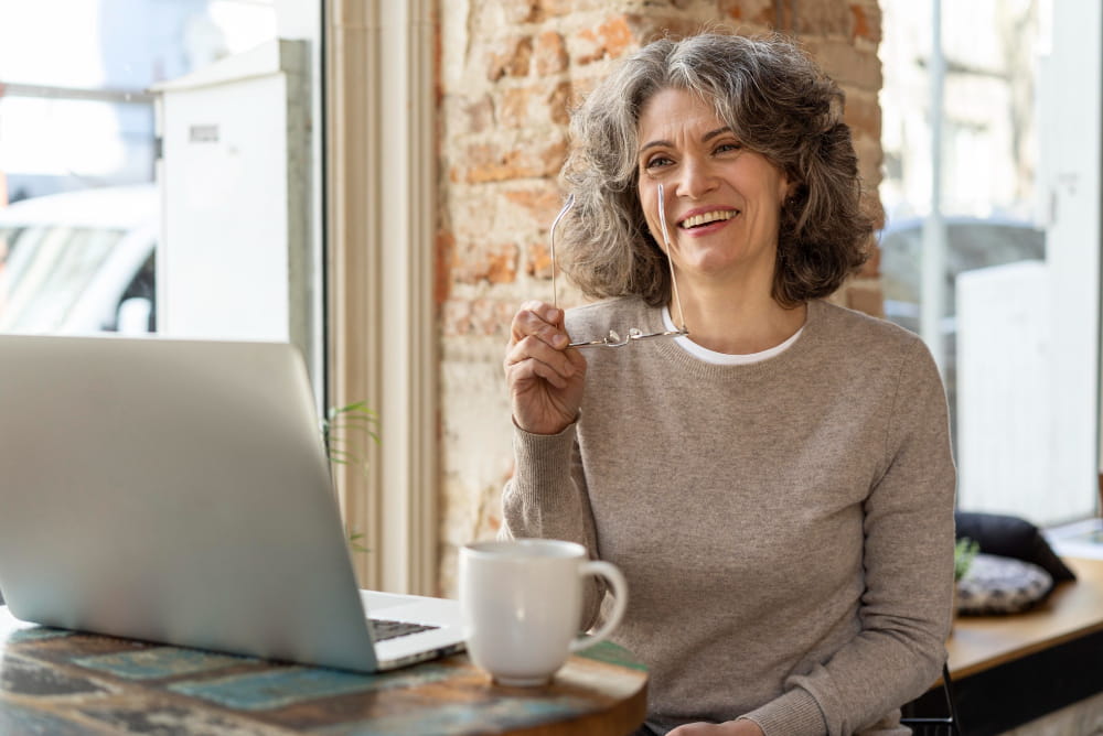 Mulher de 50 anos sorrindo em ambiente de trabalho.