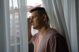 Adulto sentado em um ambiente silencioso olhando pela janela