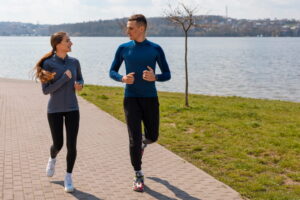 Homem e mulher praticando caminhada ou corrida em parque.