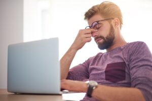 essoa trabalhando diante do computador com expressão de cansaço