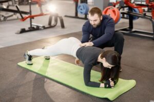 Personal trainer corrigindo a postura de um aluno durante o exercício.